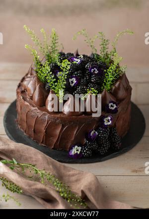 Gâteau au chocolat avec des mûres sur le dessus sur une table en bois. Gâteau d'anniversaire. Joliment décoré. Banque D'Images