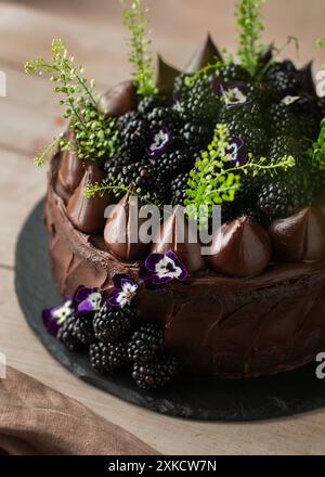 Gâteau au chocolat avec des mûres sur le dessus sur une table en bois. Gâteau d'anniversaire. Joliment décoré. Banque D'Images