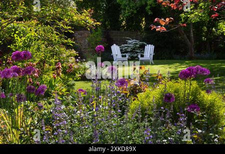 Chaises en bois blanc dans le jardin anglais d'été avec des pensionnaires de fleurs, Angleterre Banque D'Images