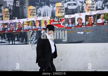 Jérusalem, Israël. 22 juillet 2024. Un israélien ultra-orthodoxe passe devant des affiches d’otages israéliens retenus en captivité par le Hamas à Gaza dans une rue de Jérusalem le lundi 22 juillet 2024. Le premier ministre israélien Benjamin Netanyahu doit rencontrer le président américain Joe Biden et s’adresser à une session conjointe du Congrès à Washington, DC cette semaine, tandis qu’une majorité de l’opinion publique israélienne affirme qu’il a saboté un accord d’otages pour sa survie politique. Photo de Debbie Hill/ crédit : UPI/Alamy Live News Banque D'Images