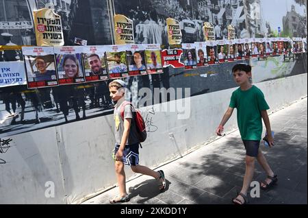 Jérusalem, Israël. 22 juillet 2024. Des garçons israéliens passent devant des affiches d’otages israéliens retenus en captivité par le Hamas à Gaza dans une rue de Jérusalem le lundi 22 juillet 2024. Le premier ministre israélien Benjamin Netanyahu doit rencontrer le président américain Joe Biden et s’adresser à une session conjointe du Congrès à Washington, DC cette semaine, tandis qu’une majorité de l’opinion publique israélienne affirme qu’il a saboté un accord d’otages pour sa survie politique. Photo de Debbie Hill/ crédit : UPI/Alamy Live News Banque D'Images