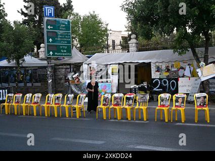 Jérusalem, Israël. 22 juillet 2024. Une femme tient une pancarte derrière des chaises jaunes vides avec des affiches d’otages israéliens retenus captifs par le Hamas à Gaza dans une rue de Jérusalem le lundi 22 juillet 2024. Le premier ministre israélien Benjamin Netanyahu doit rencontrer le président américain Joe Biden et s’adresser à une session conjointe du Congrès à Washington, DC cette semaine, tandis qu’une majorité de l’opinion publique israélienne affirme qu’il a saboté un accord d’otages pour sa survie politique. Photo de Debbie Hill/ crédit : UPI/Alamy Live News Banque D'Images