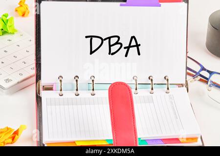 Lettres DBA ou Doctor of Business Administration dans un cahier ouvert sur fond blanc Banque D'Images