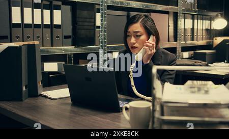 Officier de justice vérifiant les détails de l'enquête privée, travaillant dans la salle des archives. Le détective recoupe les informations sur les appels téléphoniques fixes et contacte les personnes à partir des dossiers. Caméra B. Banque D'Images