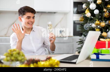 homme communique joyeusement par appel vidéo le soir du nouvel an Banque D'Images