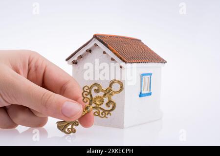 Main tenant une clé d'or près d'une maison sur un fond blanc Banque D'Images