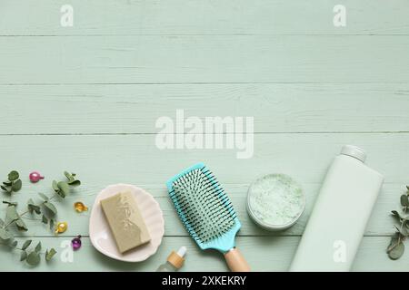 Brosse à cheveux avec des bouteilles de produits cosmétiques, savon et capsules sur fond de bois vert Banque D'Images