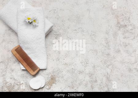 Belle composition avec des serviettes douces propres, peigne en bois, tampons de coton et fleur de coton sur fond grunge Banque D'Images