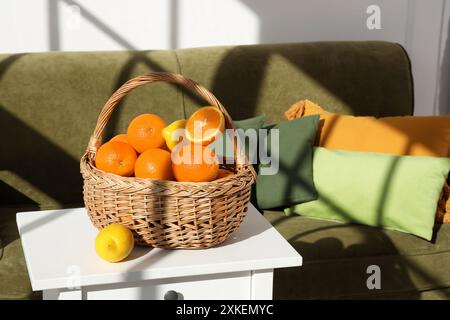 Panier en osier avec des agrumes sur la table basse près du canapé dans le salon Banque D'Images