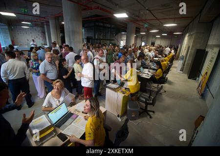 Bucarest, Roumanie. 22 juillet 2024 : des volontaires aident les gens à remplir 'le contrat d'inscription au plan Simion', lors d'une action de campagne présidentielle de George Simion, le candidat du parti populiste et nationaliste de droite Aur (Alliance pour l'Union des Roumains), à son siège de campagne dans le magasin de Bucarest. « Le plan Simion » vise à faciliter l’achat sans intérêt d’un appartement à partir de 35 000 euros et le refinancement, sans intérêt et autres coûts entièrement subventionnés par l’Etat, des prêts hypothécaires existants entre 35 000 et 70 000 euros. Crédit : Lucian Banque D'Images