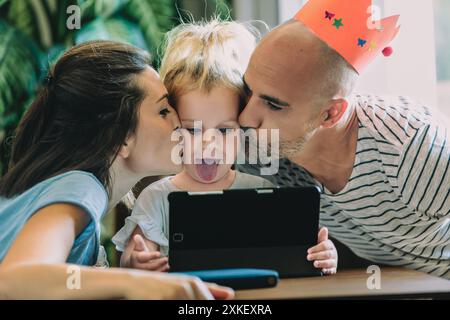 Une famille heureuse partage un moment d'amour, embrassant leur enfant ravi Banque D'Images