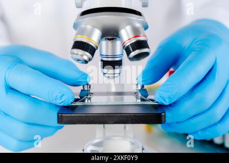 Scientifique utilisant le microscope en laboratoire, faisant des tests médicaux et de la recherche. Gros plan d'un microscope avec lentille métallique au laboratoire. Banque D'Images