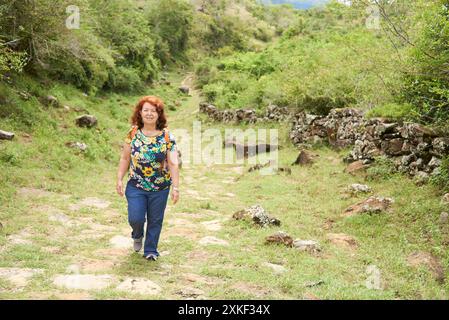 Femme hispanique mature profitant d'une randonnée sur un sentier rural, une voie royale en pierre restaurée, allant de Barichara à Guane, à Santander, en Colombie. Concept : AC Banque D'Images