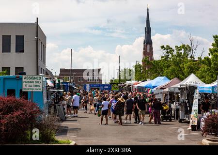 Paul's Lutheran Church s'élève au-dessus des clients parcourant une rangée d'étals de vendeurs au marché YLNI Famers Market dans le centre-ville de Fort Wayne, Indiana, USA. Banque D'Images