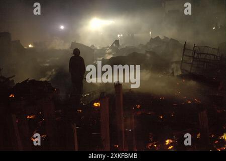 Un pompier effectuant la phase de refroidissement après un incendie a brûlé des centaines de maisons dans un quartier dense de Jakarta, en Indonésie. Banque D'Images