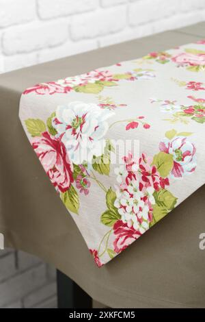 Chemin de table floral sur une nappe beige contre un mur de briques blanches Banque D'Images