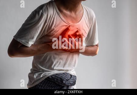 Jeune asiatique souffrant de douleurs thoraciques centrales. La douleur thoracique peut être causée par une crise cardiaque, un infarctus du myocarde ou une ischémie, une myocardite, une pneumonie, s. Banque D'Images