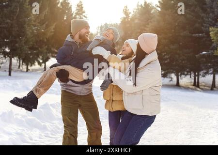 Famille heureuse avec des enfants debout à l'extérieur profitant de la belle nature dans la forêt d'hiver. Banque D'Images