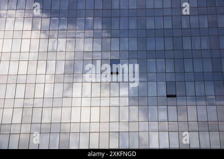 Un bâtiment reflète un ciel bleu dans ses fenêtres, avec une forme rectangulaire, des couleurs grises, des matériaux composites, du bois, des teintes, nuances, motifs, symétrie Banque D'Images