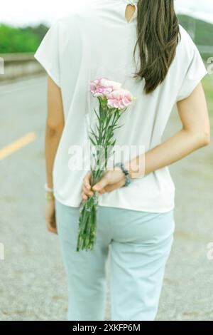 Fermez la main de la femme tenant des fleurs d'oeillet sur fond flou. Banque D'Images