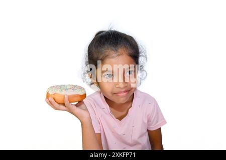 Cette petite fille est confrontée à un choix difficile : partager le délicieux beignet ou le garder pour elle-même? Banque D'Images