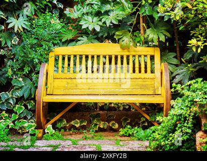 Vieux banc en bois jaune dans le jardin. Style vintage Banque D'Images