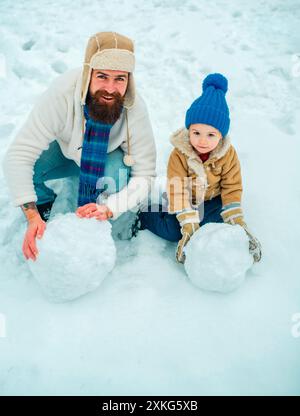 Fête de Noël. Fête des pères. Vacances de Noël. Père et fils jouent en vêtements d'hiver. Portrait hivernal de papa et enfant dans Snow Garden Banque D'Images