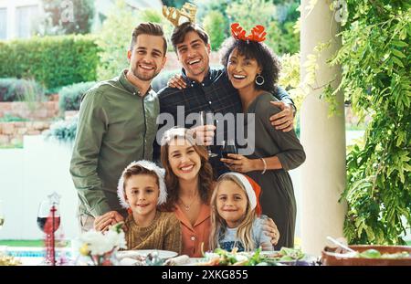 Amis, famille et enfants dans le portrait de Noël pour le déjeuner, la célébration et le sourire dans l'arrière-cour à la maison. Hommes, femmes et enfants sur le patio ensemble pour Banque D'Images