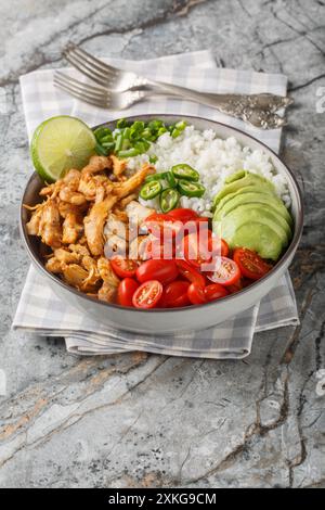 Bol de riz mexicain avec carnitas de poulet, tomates cerises, avocat, poivrons gros plan sur la table. Vertical Banque D'Images