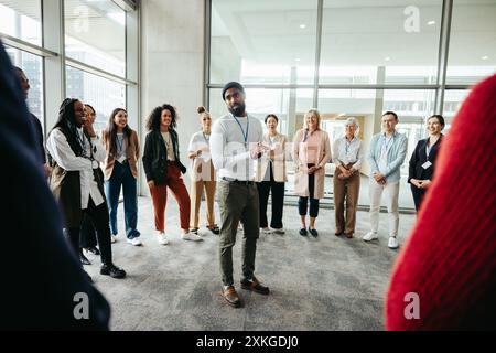 L'instructeur guide l'exercice de consolidation d'équipe lors de la conférence avec un groupe diversifié de personnes. Concept de travail d'équipe, de communication et d'apprentissage dans une profession Banque D'Images