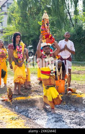 Un fidèle hindou pieux marche pieds nus sur des charbons brûlants au Thimithi Fire Walking Festival au Arya Spiritual Grounds à Jamaica, Queens, NY Banque D'Images