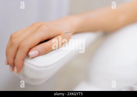Gros plan recadré d'une jeune femme avec des aiguilles d'acupuncture à la main. Gros plan d'une patiente détendue recevant une procédure d'acupuncture corporelle couchée Banque D'Images