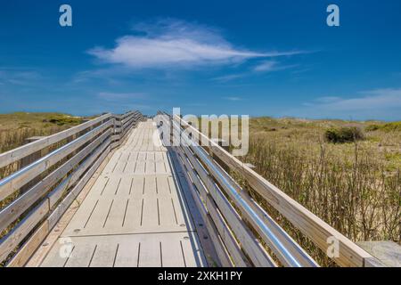 Rampe en bois mène au sommet d'une dune de sable couverte d'herbe où une vue sur l'océan Atlantique vous attend. Banque D'Images