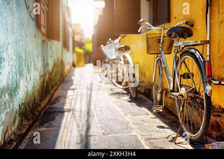 Vélos garés près du mur jaune de la vieille maison sur la rue ensoleillée Banque D'Images
