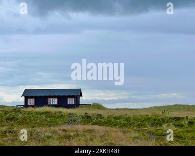 Une maison pittoresque solitaire dans le style danois sur une prairie sous le ciel nuageux sombre avant la pluie, Skagen, sur le chemin du cap Grenen. Banque D'Images