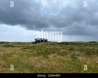 Une maison pittoresque solitaire dans le style danois sur une prairie sous le ciel nuageux sombre avant la pluie, Skagen, sur le chemin du cap Grenen. Banque D'Images