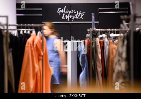 Berlin, Allemagne. 23 juillet 2024. Une femme passe devant des rails de vêtements dans le grand magasin de luxe Galeries Lafayette sur Friedrichstrasse à Berlin-Mitte. La chaîne de grands magasins française Galeries Lafayette ferme fin juillet 2024 son agence berlinoise dans le quartier 207. Le Sénat de Berlin envisage d'emménager la Bibliothèque centrale et régionale de Berlin (ZLB) dans le complexe. Crédit : Bernd von Jutrczenka/dpa/Alamy Live News Banque D'Images