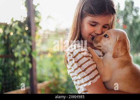 Portrait en gros plan d'une petite fille serrant un chiot dans ses bras. Un petit enfant mignon joue avec un chien. Un enfant doux est heureux avec son animal de compagnie. Un joli GI préscolaire Banque D'Images