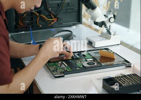 Technicien examinant la carte mère avec loupe Banque D'Images