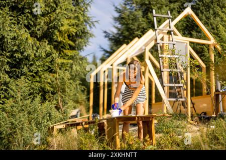 Femme construisant une serre en bois à l'arrière-cour Banque D'Images