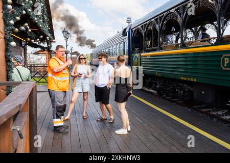 Sortavala, Russie - 21 juillet 2024 : les passagers du train d'époque Ruskeala Express discutent avec un ingénieur assistant de locomotive à vapeur Banque D'Images