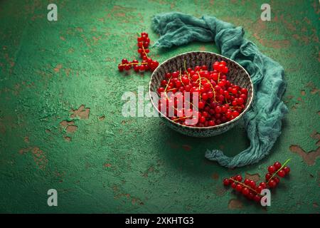 Groseilles rouges biologiques dans un bol sur fond vert Banque D'Images