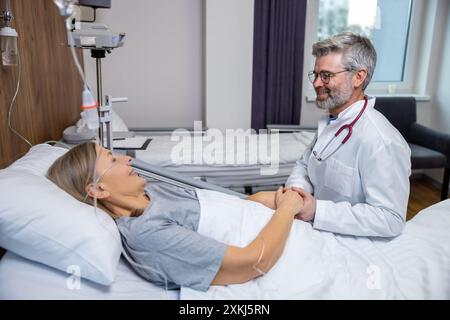 Docteur parlant à une patiente et tenant ses mains Banque D'Images