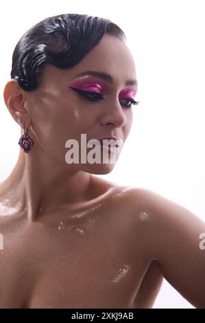 Portrait studio d'une femme avec le maquillage des yeux rose frappant et la coiffure d'onde de doigt regardant vers le bas. L'image transmet l'élégance, la beauté et la confiance. Banque D'Images