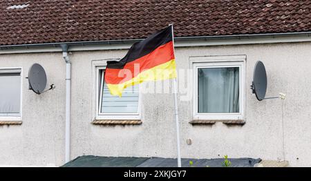 Hambourg, Allemagne. 13 juillet 2024. Un drapeau allemand flotte devant une maison mitoyenne. Crédit : Markus Scholz/dpa/Alamy Live News Banque D'Images