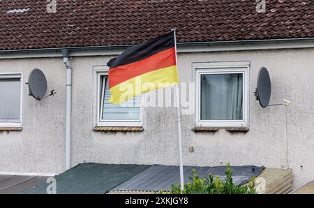 Hambourg, Allemagne. 13 juillet 2024. Un drapeau allemand flotte devant une maison mitoyenne. Crédit : Markus Scholz/dpa/Alamy Live News Banque D'Images