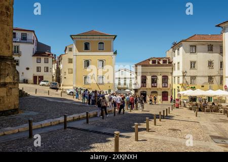 Vue de Largo da Sé Velha avec l'ombre des remparts de la cathédrale sur le trottoir et les touristes visitant la ville de Coimbra, Portugal, Europe. Banque D'Images