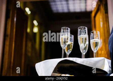 Serveur tenant un plateau avec des flûtes à champagne, prêt à servir lors d'un événement formel. Photo horizontale Banque D'Images