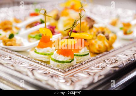 Canapés avec saumon fumé, fromage à la crème, concombre et poivron jaune sur un plateau en argent lors d'un événement traiteur Banque D'Images