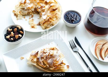 Une tranche de tarte aux pommes ou un dessert de pâte phyllo sur une assiette blanche sur un fond clair avec des noix et de la confiture. Foyer sélectionné. Photo de haute qualité Banque D'Images
